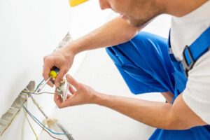 Eletricista desencapando um fio de energia